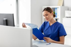 a women in hospital scrubs sitting at computer doing paper work